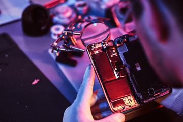 The technician carefully examines the integrity of the internal elements of the smartphone in a...