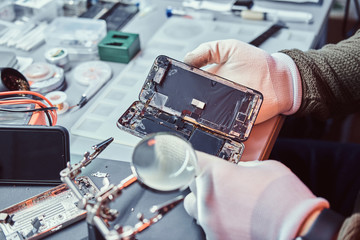 Fototapeta na wymiar The technician carefully examines the integrity of the internal elements of the smartphone in a modern repair shop