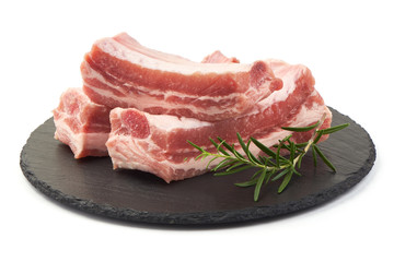 Raw fresh pork ribs with rosemary on a slate shale plate, close-up, isolated on white background