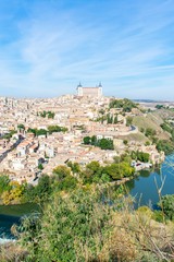 Fototapeta na wymiar A panoramic view of the old city of Toledo, with it’s castle inside the city walls, surrounded by a ravine and river that serves as a moat.
