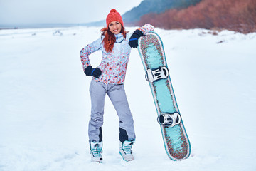 Young joyful snowboarder woman smiling and posing on the ski track