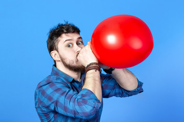Man inflating a red balloon by mouth, image on a blue background