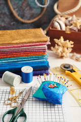 Accessories for quilting and a stack of colorful fabrics for quilting on the background of the box...