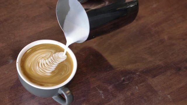Professional Barista making pouring stream milk with latte art pattern.