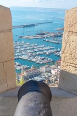 A rusty old canon points out towards the Mediterranean taking aim at the modern marina and the city below