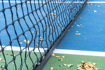 Black woven net on hardcourt surface tennis court in game/sports outdoor park.