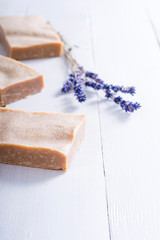handmade soaps and dried lavender flowers on white wood table background