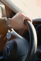 Man hand with clock driving  car holding black steering wheel. Vertical foto