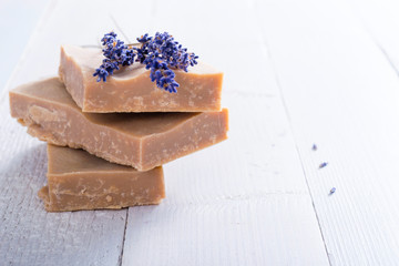handmade soaps and dried lavender flowers on white wood table background