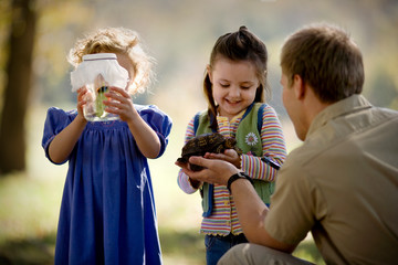 Mid adult man hands a turtle to his daughter.