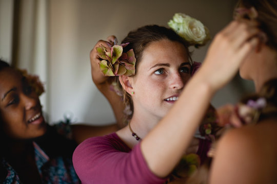 Teenage girls dressing each other's hair with roses.