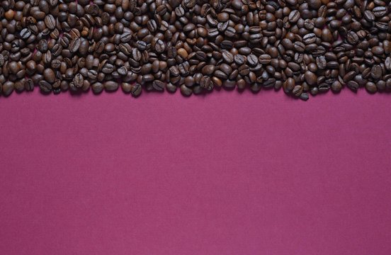 Roasted coffee beans on a burgundy background © Viacheslav