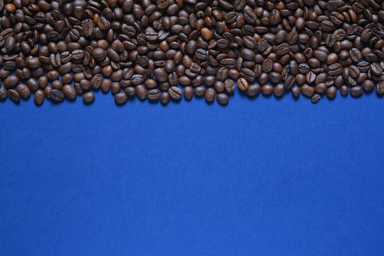 Roasted coffee beans on a blue background © Viacheslav