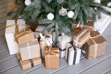 Fototapeta na wymiar Christmas gifts in beautiful packages decorated with ribbons with a bow under the Christmas tree