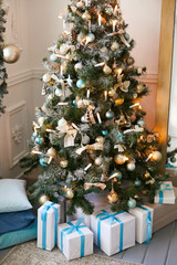 Luxurious Christmas tree in a residential building decorated with many toys and balls. Gifts under the tree.
