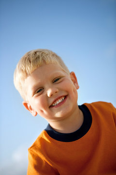 Portrait of a smiling young boy under blue sky.