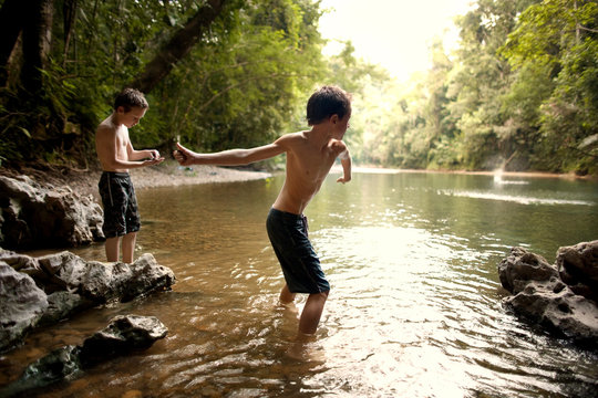 One man shows his son how to skim stones across water.