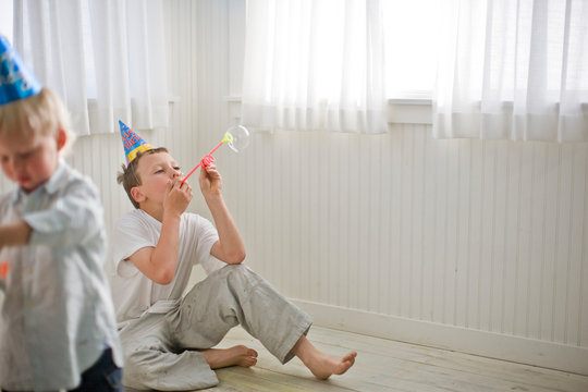 Boys Wearing Party Hats and Blowing Bubbles