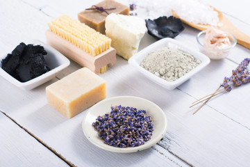 spa massage mud and clay powder, soaps, bath salt, shea butter and lavenders on white wood table background