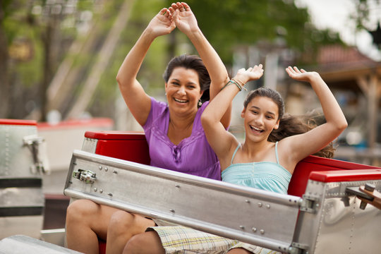 Happy mother and daughter on a ride at an amusement park.