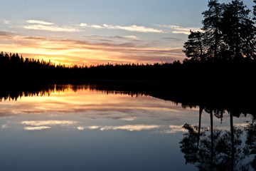 sunset clouds are reflected in the calm mirror water of the lake