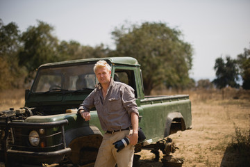 Mid-adult man standing beside a safari truck.
