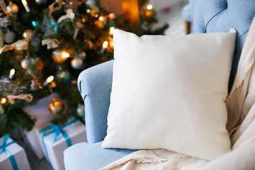Blue soft armchair with a pillow next to the Christmas tree