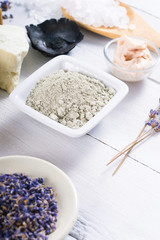 spa massage mud and clay powder, soaps, bath salt, shea butter and lavenders on white wood table background