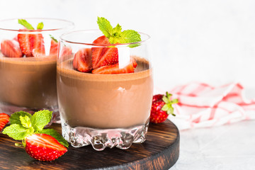 Chocolate dessert of whipped cream and strawberries in glass.