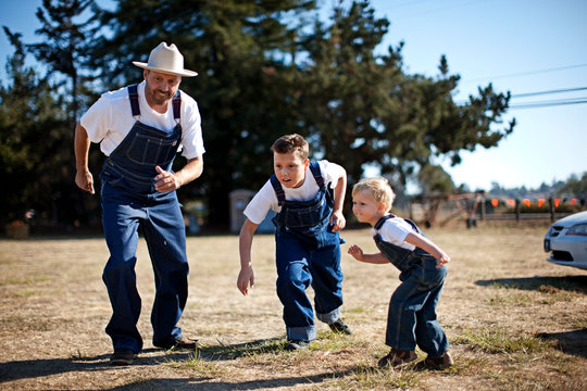Father and two sons wearing matching denim overalls about to race