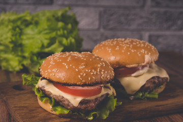 Нamburger or sandwich on brown paper. Delicious sandwich hamburger with meat, cheese and fresh vegetable. Hamburger or sandwich is the popular fast food for brunch or lunch. Juicy cheeseburger