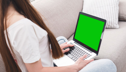 Woman typing on laptop keyboard with green screen