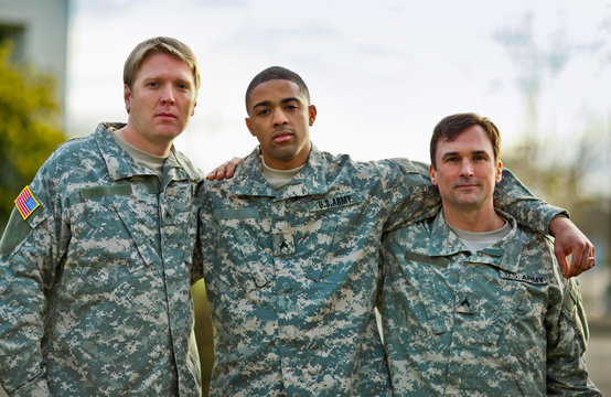 Portrait of three US Army soldiers with their arms around each other.