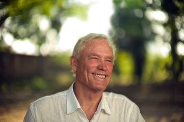Smiling mature man poses for a portrait in a park.