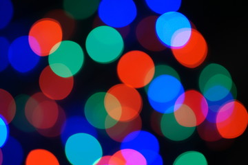 Multi-color blue holiday garland. Garland is blurred. Many big colorful round lights. Fully defocused photo. Blurred background and foreground. Holiday mood. New Year and Christmas is coming.