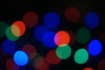 Multi-color blue holiday garland. Garland is blurred. Many big colorful round lights. Fully defocused photo. Blurred background and foreground. Holiday mood. New Year and Christmas is coming.