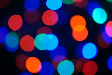 Multi-color blue holiday garland. Garland is blurred. Many big colorful round lights. Fully defocused photo. Blurred background and foreground. Holiday mood. New Year and Christmas is coming.