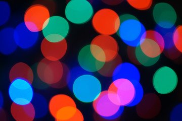 Multi-color blue holiday garland. Garland is blurred. Many big colorful round lights. Fully defocused photo. Blurred background and foreground. Holiday mood. New Year and Christmas is coming.