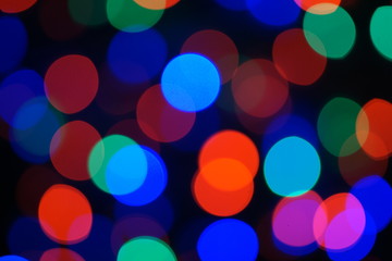 Multi-color blue holiday garland. Garland is blurred. Many big colorful round lights. Fully defocused photo. Blurred background and foreground. Holiday mood. New Year and Christmas is coming.