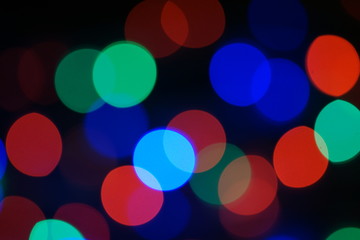 Multi-color blue holiday garland. Garland is blurred. Many big colorful round lights. Fully defocused photo. Blurred background and foreground. Holiday mood. New Year and Christmas is coming.