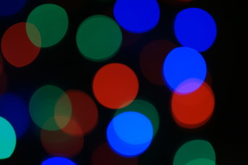 Multi-color blue holiday garland. Garland is blurred. Many big colorful round lights. Fully defocused photo. Blurred background and foreground. Holiday mood. New Year and Christmas is coming.
