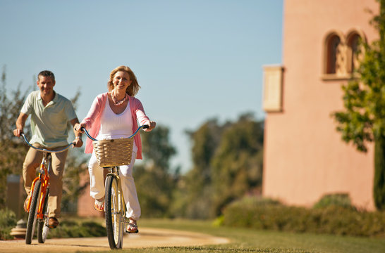 Portrait of a smiling mid adult woman riding a bicycle with her husband.
