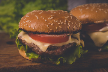 Нamburger or sandwich on brown paper. Delicious sandwich hamburger with meat, cheese and fresh vegetable. Hamburger or sandwich is the popular fast food for brunch or lunch. Juicy cheeseburger