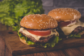 Нamburger or sandwich on brown paper. Delicious sandwich hamburger with meat, cheese and fresh vegetable. Hamburger or sandwich is the popular fast food for brunch or lunch. Juicy cheeseburger