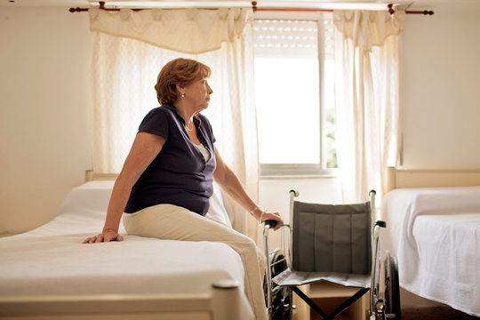 Mature female patient sitting on hospital bed.