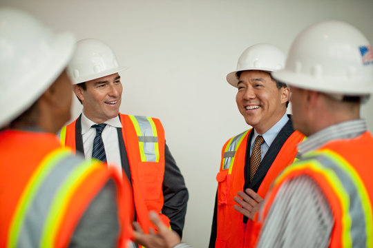 Businessmen meeting with construction workers on a building site.