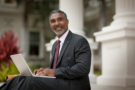 Smiling businessman using a laptop computer.