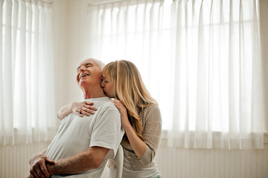 Young woman kissing her grandfather on the neck.