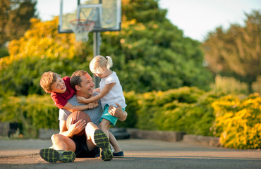 Smiling father playing basketball with his young children.