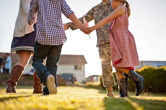 Low section of soldier dancing with family in backyard
